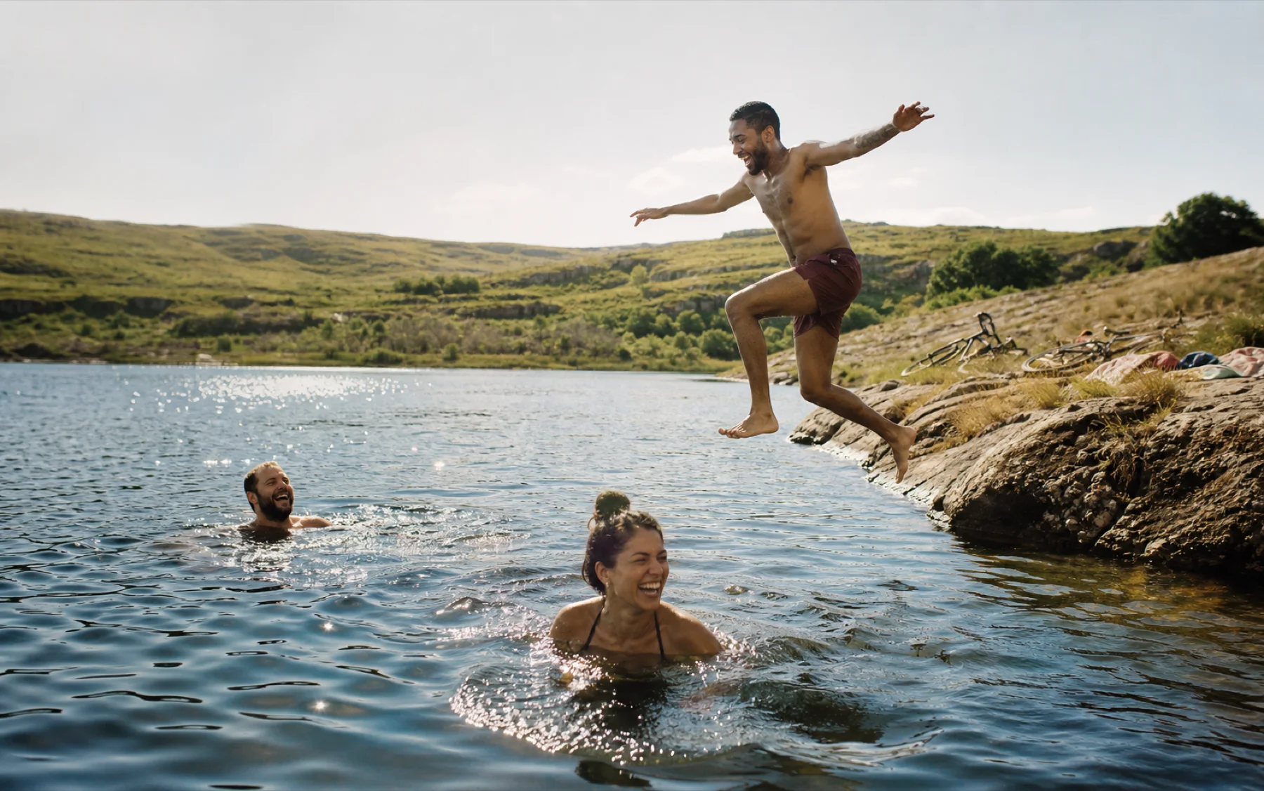 Friends laughing and jumping into a lake on a sunny afternoon